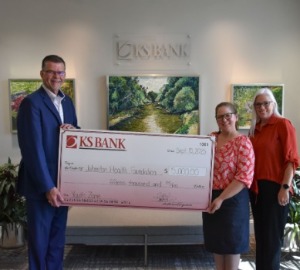 Bank CEO presenting $15,000 check to two employees of Johnston Health Foundation 